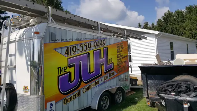 JLH Co. trailer with ladders parked beside a house with new white siding