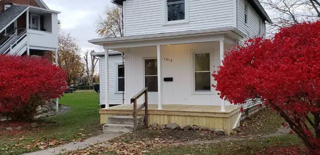 White two-story house with a rebuilt front porch, new wood decking, steps and white columns
